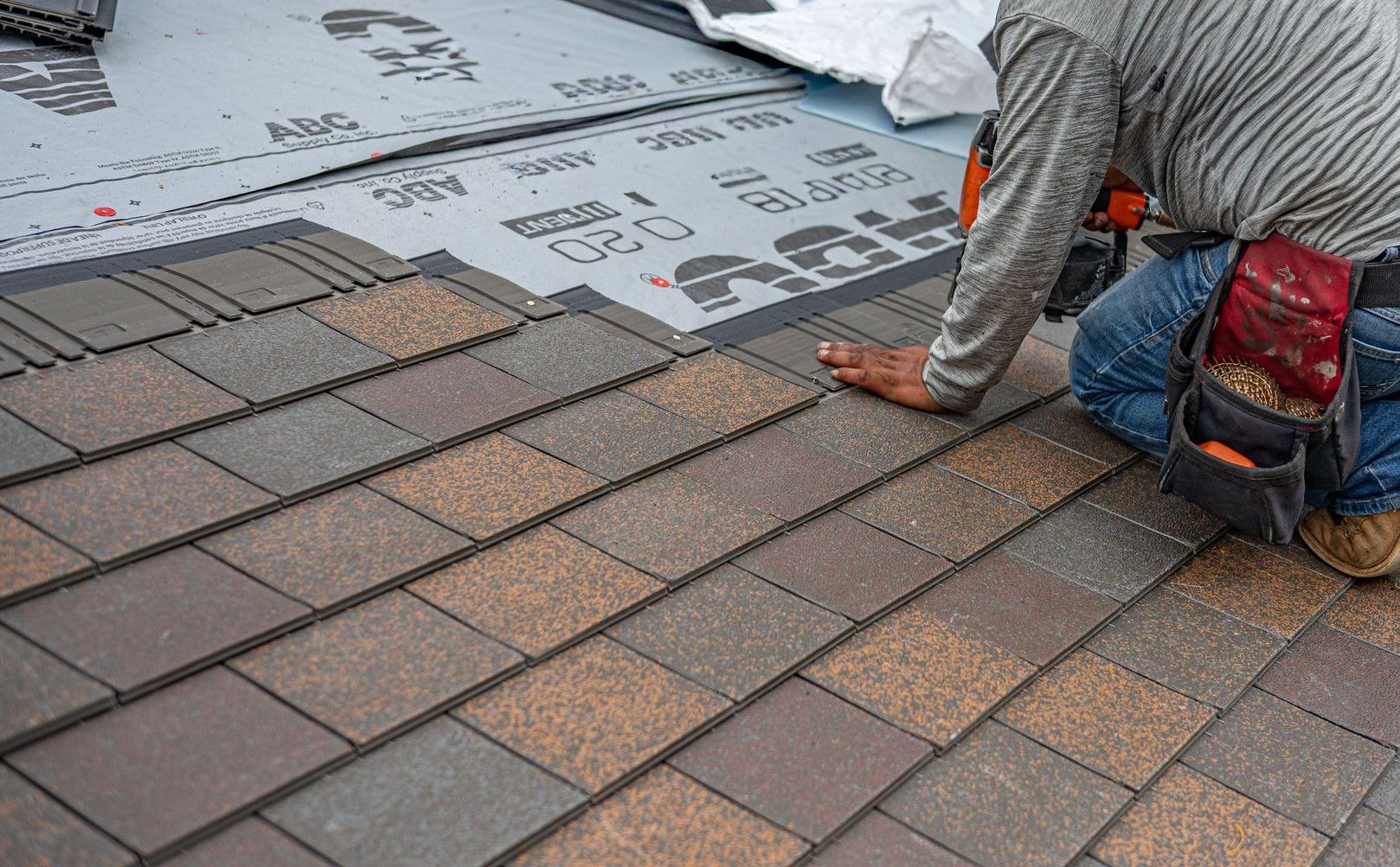 Skilled roofer installing asphalt shingles, ensuring quality home renovation.
